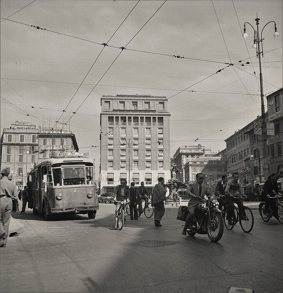 Filobus, biciclette e una motocicletta in una piazza di Roma, 1947